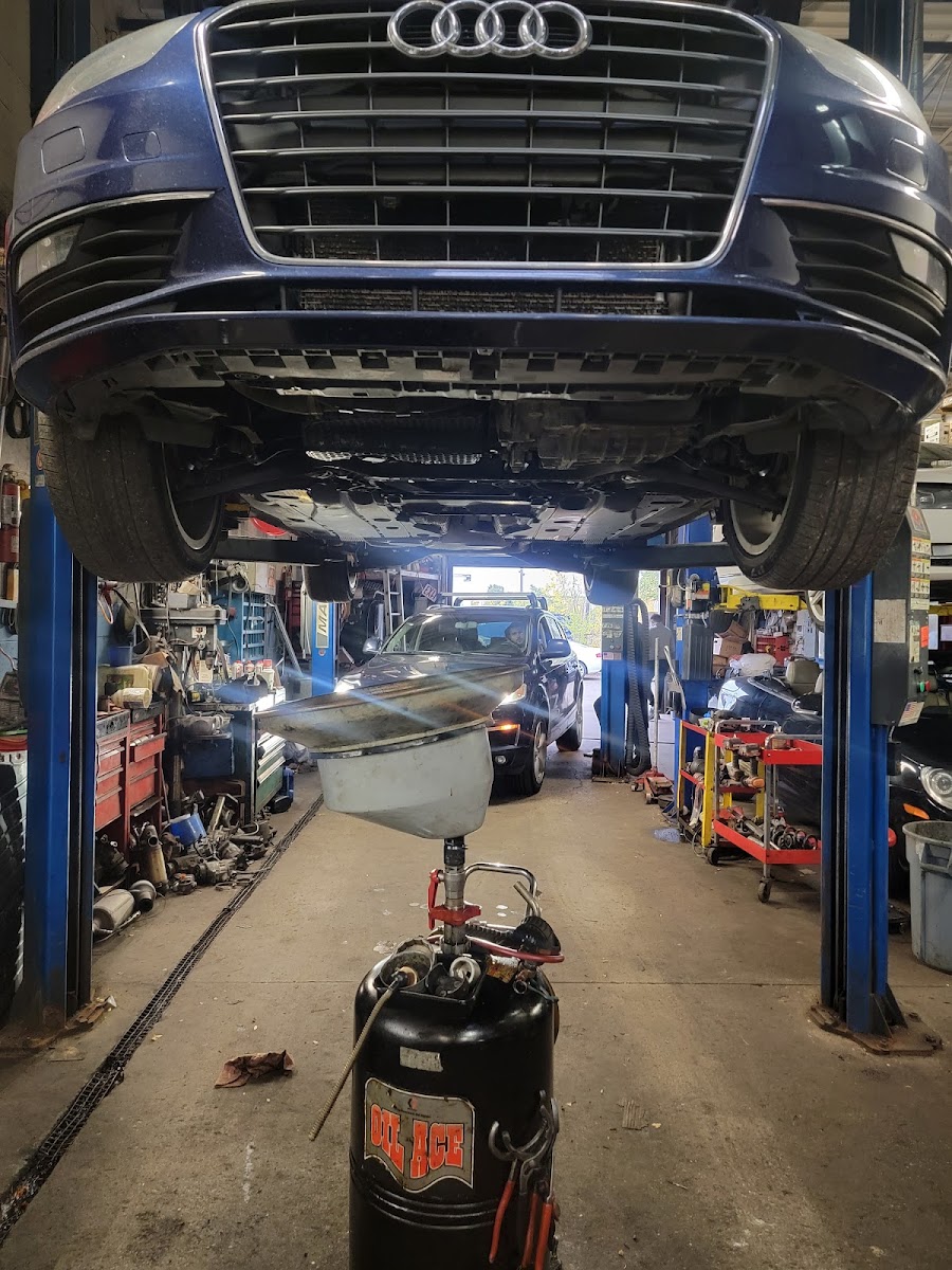 Audi sedan raised on a two-post lift, drain pan in place